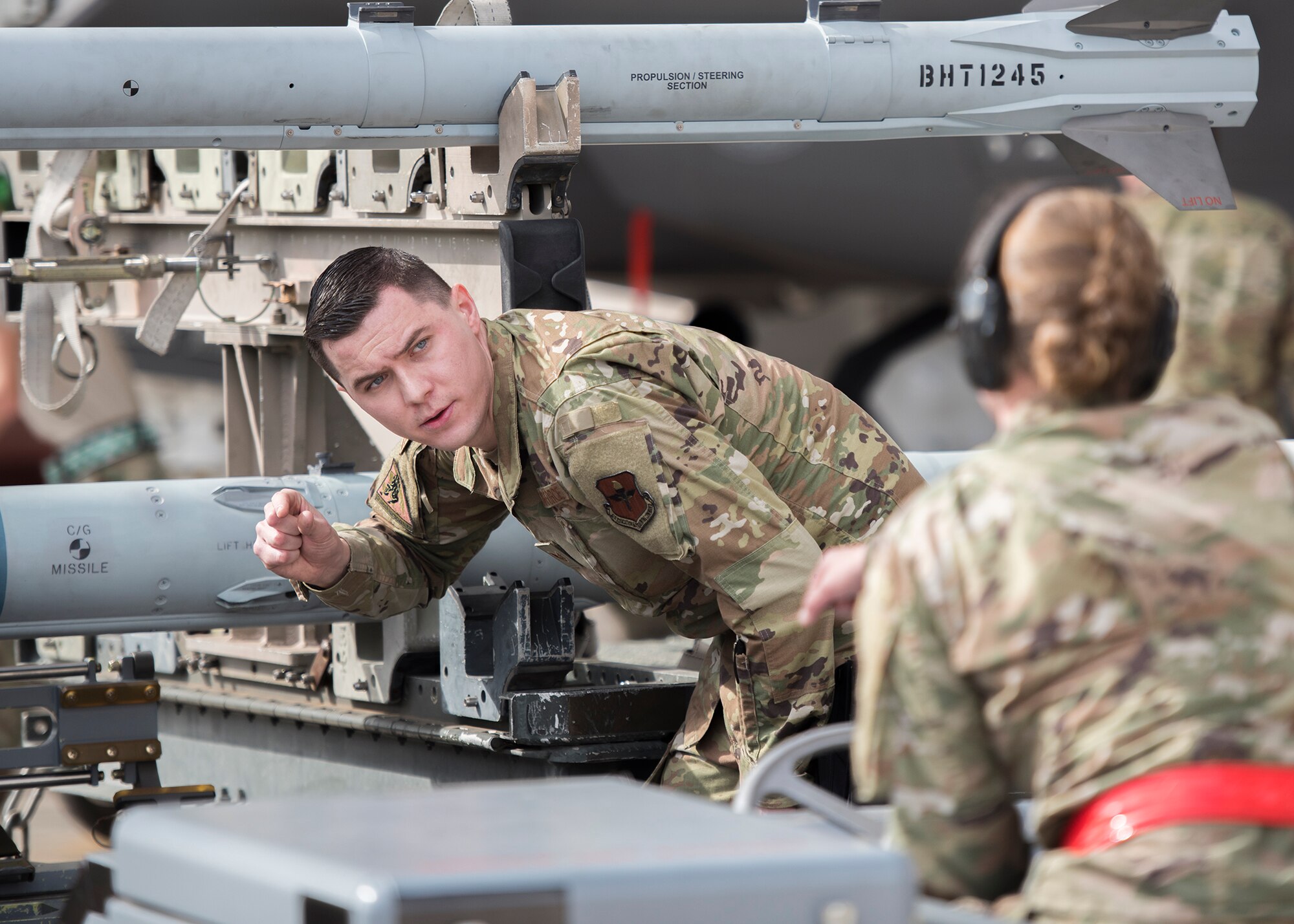 Staff Sgt. Tyler James McGovern, 63rd Aircraft Maintenance Unit weapons load crew chief, guides Airman 1st Class Amanda Knutson, 63rd AMU weapons load crew member, as she approaches an aircraft in a jammer during the Annual Load Crew Competition, Jan. 24, 2020, at Luke Air Force Base, Ariz.