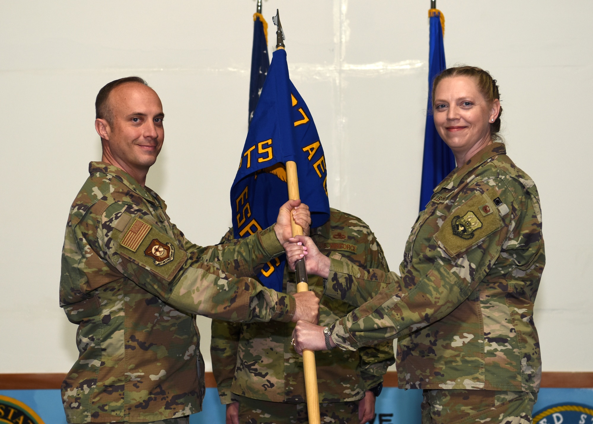 U.S. Air Force Col. David Morgan, 407th Air Expeditionary Group commander, left, passes the ceremonial guidon to Lt. Col. Michelle Gill, incoming 407th Expeditionary Support Squadron commander, right, during a change of command ceremony at Ahmed Al Jaber Air Base, Kuwait, Jan. 28 2020.