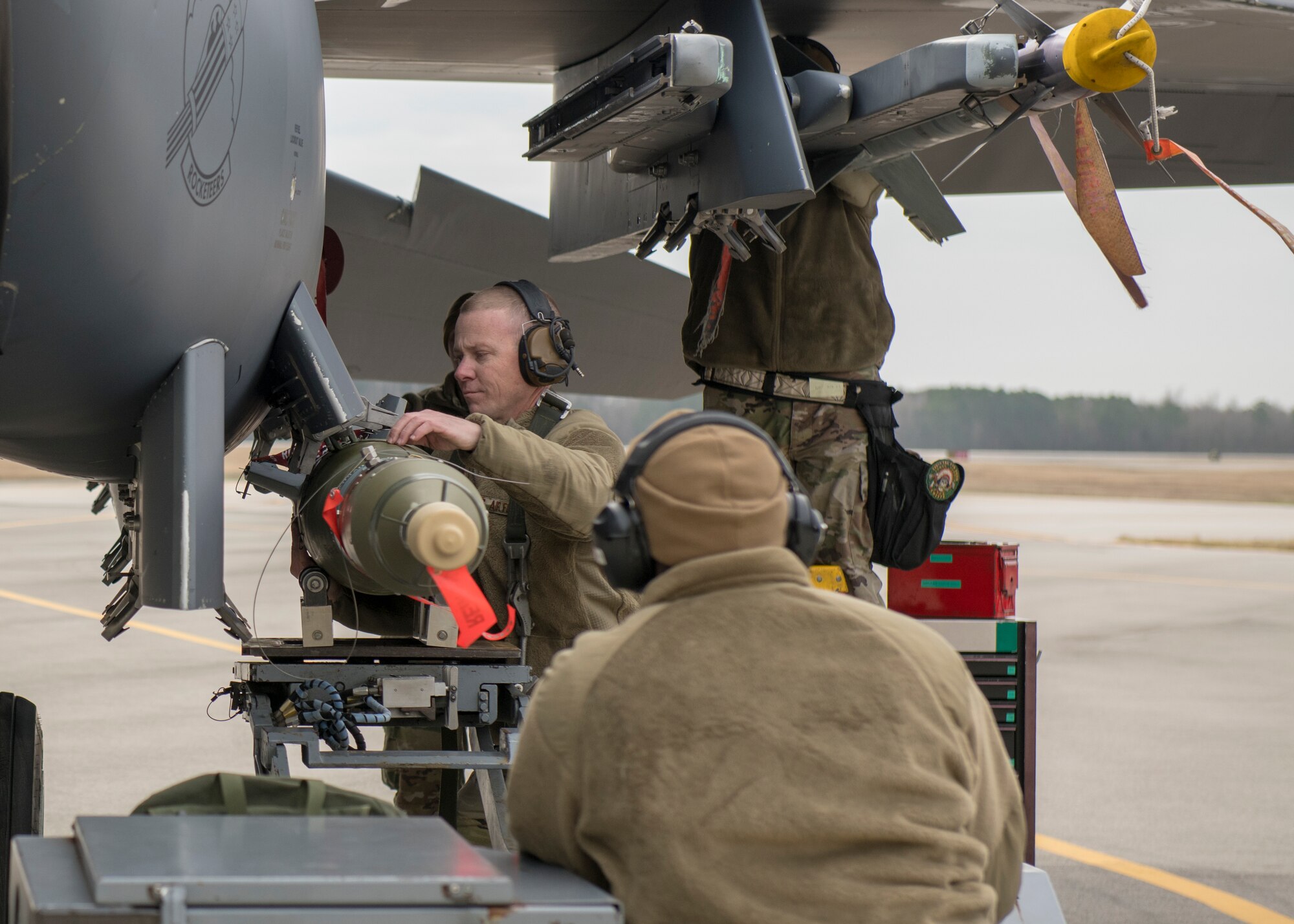 Sgt. Stephen Roberts, 335th AMU weapons load crew chief (left), and Senior Airman Andre Williams, 335th Aircraft Maintenance Unit weapons load crew member (right), work together to load a munitions onto an F-15E Strike Eagle during a quarterly Load Crew Competition.