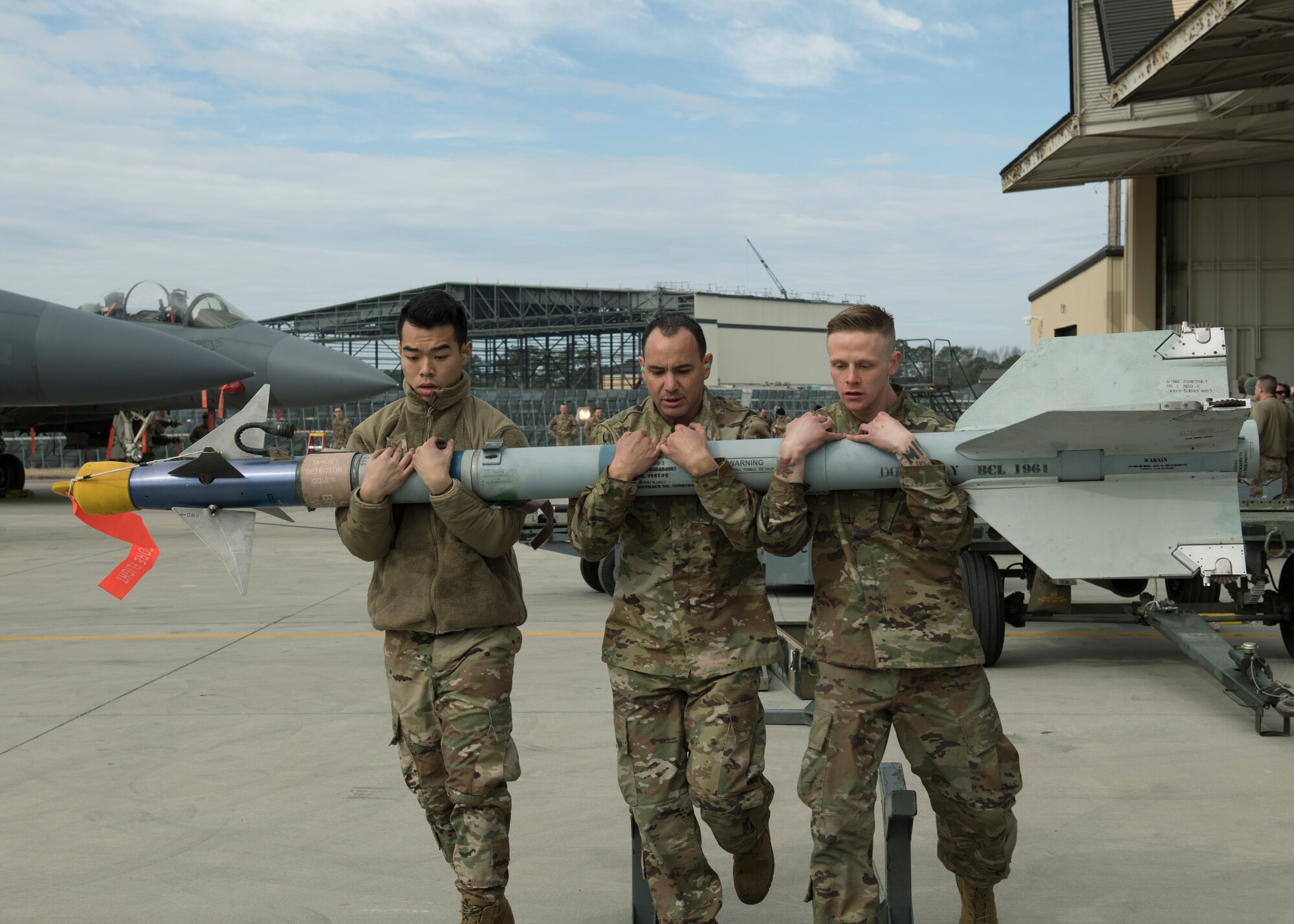 Weapons load crew members from the 336th Aircraft Maintenance Unit, carry munitions to an F-15E Strike Eagle during a quarterly Load Crew Competition.