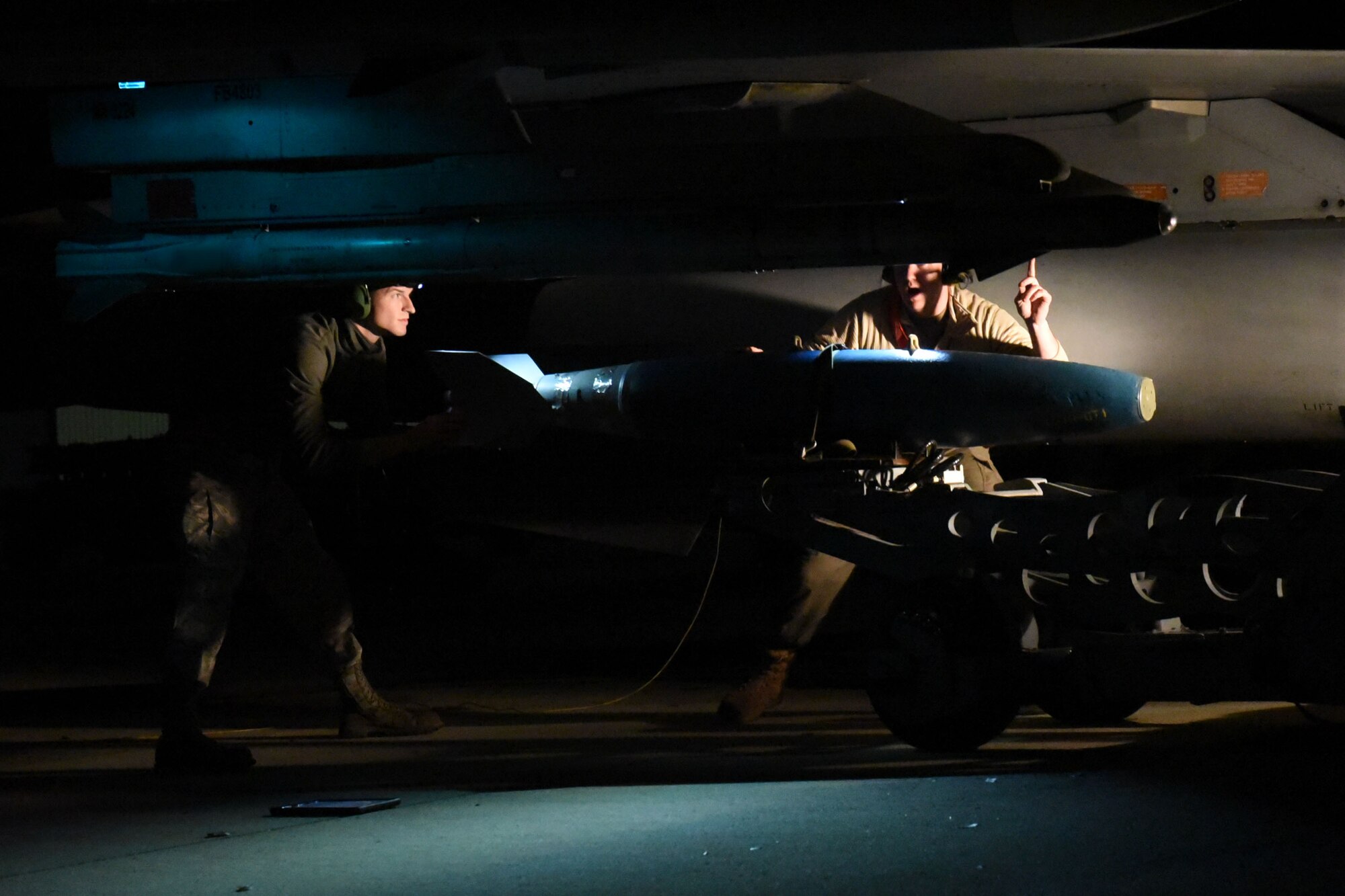 A photo of maintainers loading a munition onto an F-16 Viper.