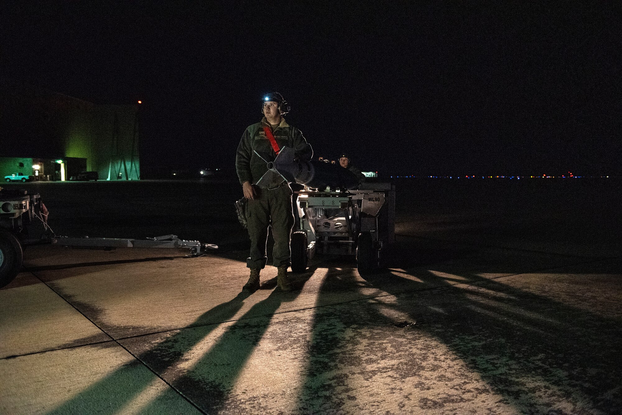 Maintainers wait with a bomb-loading vehicle for the rest of the crew to prepare an F-16 Viper for the munition.