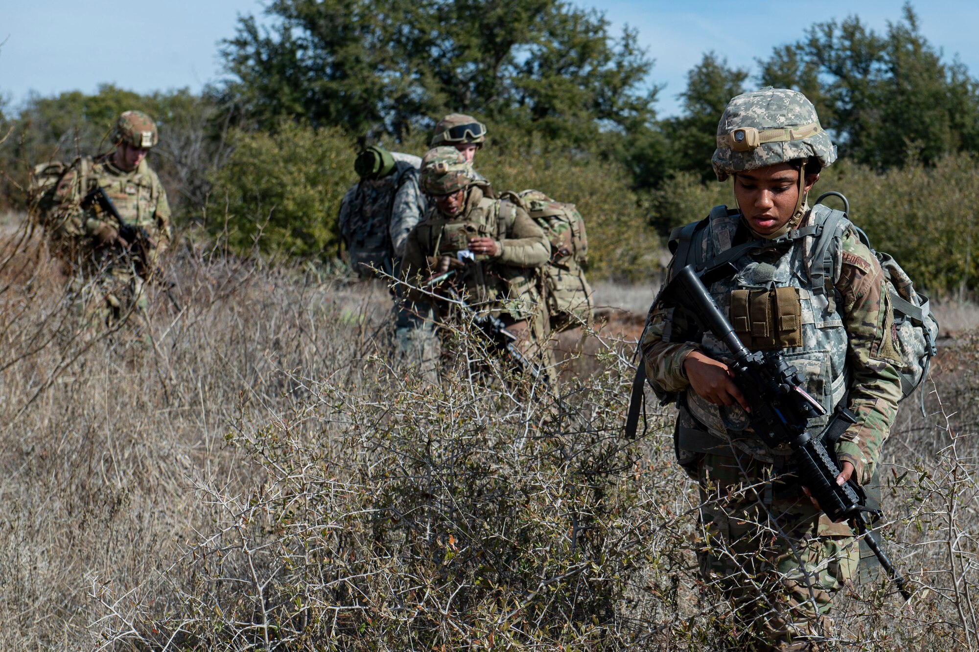 Photo of Airmen assigned to the 3d Weather Squadron navigate through grassland during a certification field exercise.