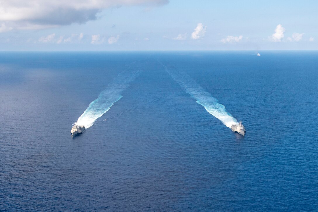 Two ships move through waters.