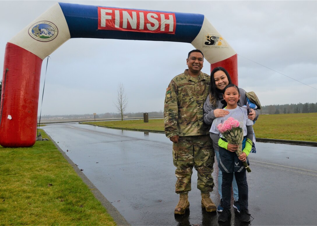 Tech. Sgt. Russell Dela Montanye of the 446th Logistics Readiness Flight smiles for a photo with his wife, April, and his daughter, Celine, during a surprise homecoming on the finish line of a 5K race hosted by I Corps and the 62nd Airlift Wing Jan. 24 to commemorate the life and legacy of Dr. Martin Luther King Jr. at Joint Base Lewis-McChord. (U.S. Army photo by Nathan Wilkes)