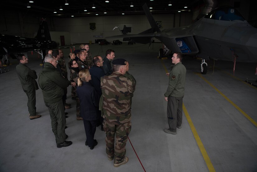 French delegates from the NATO – Allied Command Transformation receive a brief from a 1st Fighter Wing representative, during a visit to Joint Base Langley-Eustis, Virginia, Jan. 24, 2020. The representative answered various questions from the delegates about the U.S. Air Force F-22 Raptor’s real-world capabilities. (U.S. Air Force photo by Airman 1st Class Marcus M. Bullock)