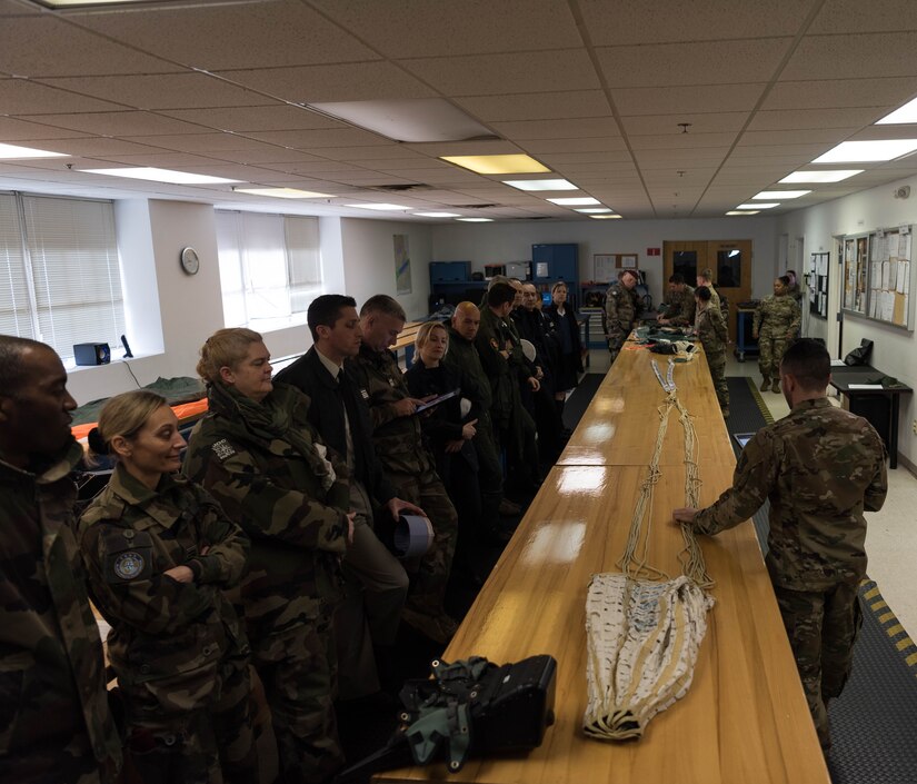 French delegates from the NATO – Allied Command Transformation receive a brief from 1st Operations Support Squadron Aircrew Flight Equipment shop during a visit to Joint Base Langley-Eustis, Virginia, Jan. 24, 2020. Here, French delegates were shown the make-up of parachute equipment used by pilots at JBLE along with survival items pilots carry for worst case scenarios. (U.S. Air Force photo by Airman 1st Class Marcus M. Bullock)