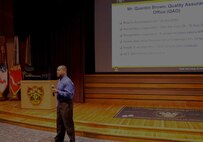 QAO Director giving a presentation in the NCOL CoE Auditorium.