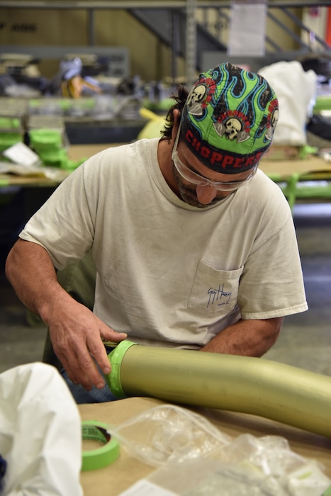 Photo shows a man putting masking tape on a tube.