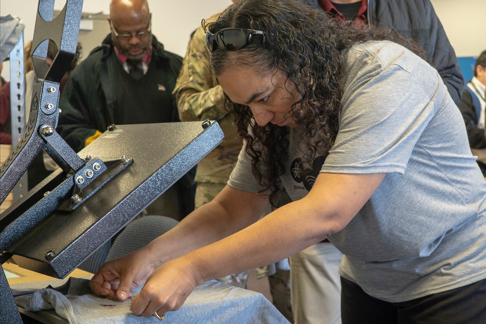 Jessica Rodriguez, a robotics team coach at Desert Jr.-Sr. High School at Edwards Air Force Base, applies a decal that was created with a 3-D printer to a T-shirt at the TechEd High School Makerspace during the grand opening at Edwards AFB, January 29. (Air Force photo by Grady T. Fontana/Released)