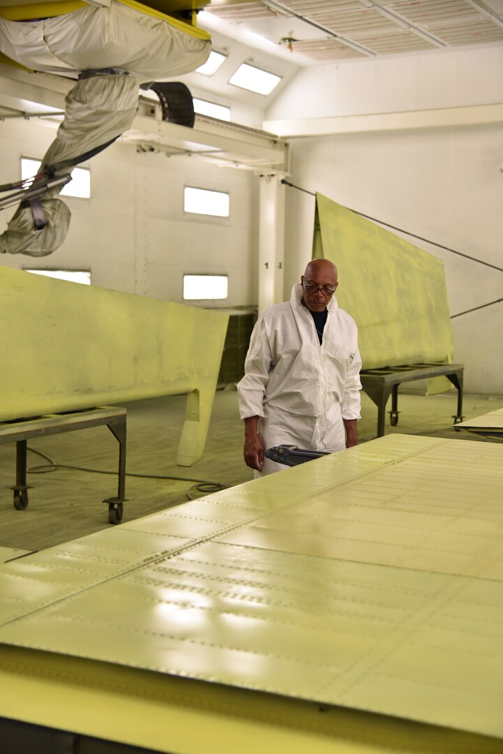 Photo shows a main checking the paint on a wing of an aircraft in the paint shop.