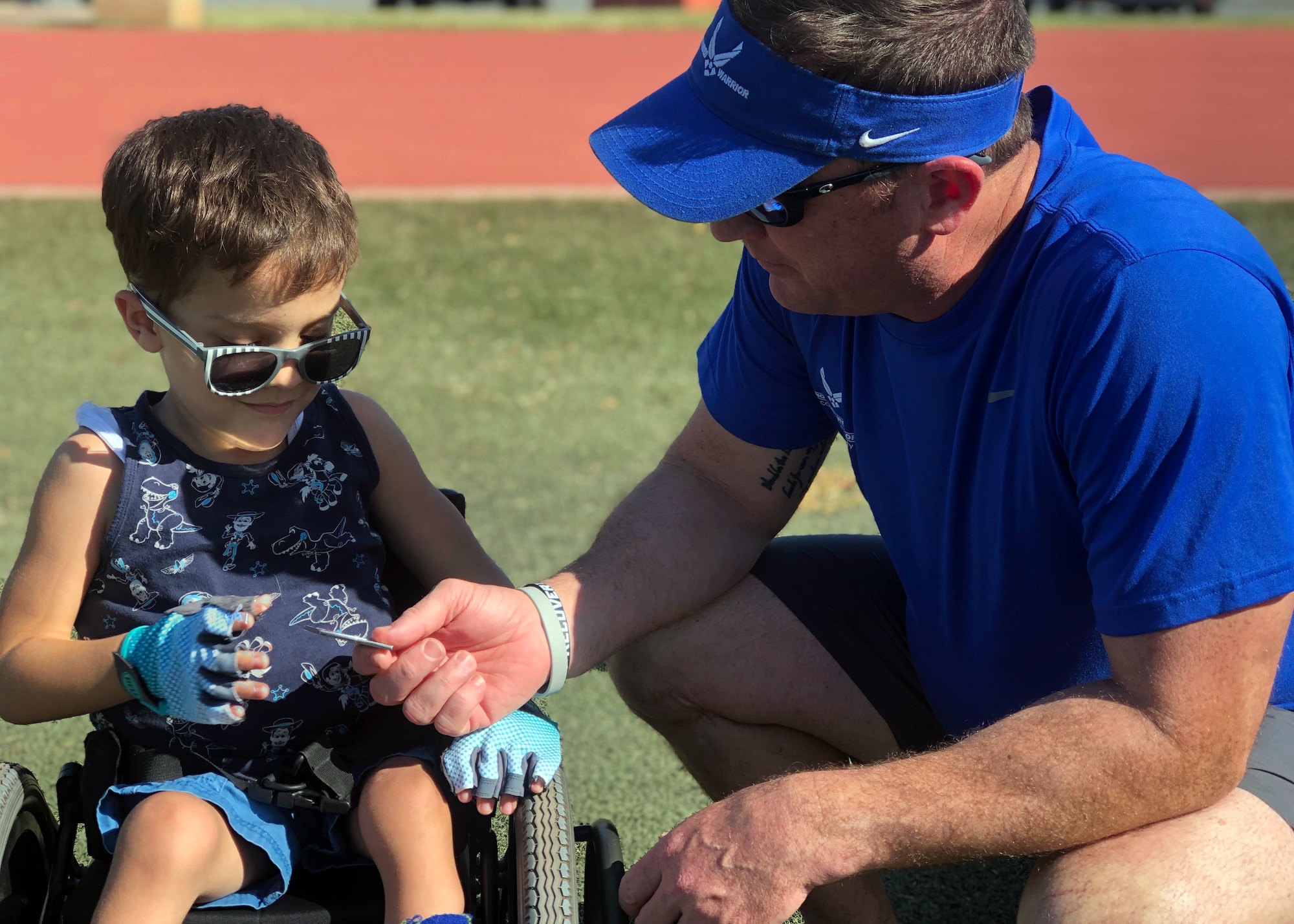 Tucker Hall, a four year old with Spina Bifida, receives a coin from Col. Michael Flatten, Air Force Wounded Warrior Program director, at the 2020 U.S. Pacific Air Forces Warrior CARE event, January 27, 2020 at Joint Base Pearl Harbor-Hickam. Tucker, the son of a volunteer at the event, was brought to the event to witness the service men and women who participate in the adaptive sports program and witness the resiliency of the warriors who do not let their illnesses or injuries define them. (Courtesy photo)