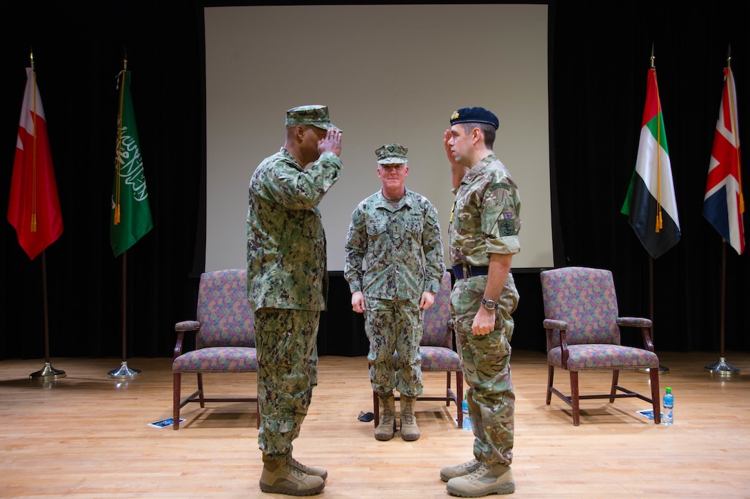 Rear Adm. Alvin Holsey (left), commander of the International Maritime Security Construct (IMSC), salutes Royal Navy Commodore James Parkin (right) during a change of command ceremony for the IMSC. Holsey was relieved by Parkin during the ceremony. IMSC maintains the freedom of navigation, international law, and free flow of commerce to support regional stability and security of the maritime commons.