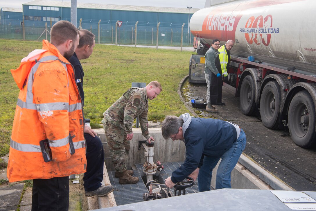 Master Sgt. Joseph Feiss, 100th Logistics Readiness Squadron noncommissioned officer in charge of fuels environmental safety office, and Alan VanDriesen, Maytag Aircraft Corporation terminal superintendent, open the valve to storage facilities Jan. 27, 2020, at RAF Mildenhall, England. The pipes must be opened to allow fuel to flow from the tanker truck into the underground tanks. (U.S. Air Force photo by Airman 1st Class Joseph Barron)
