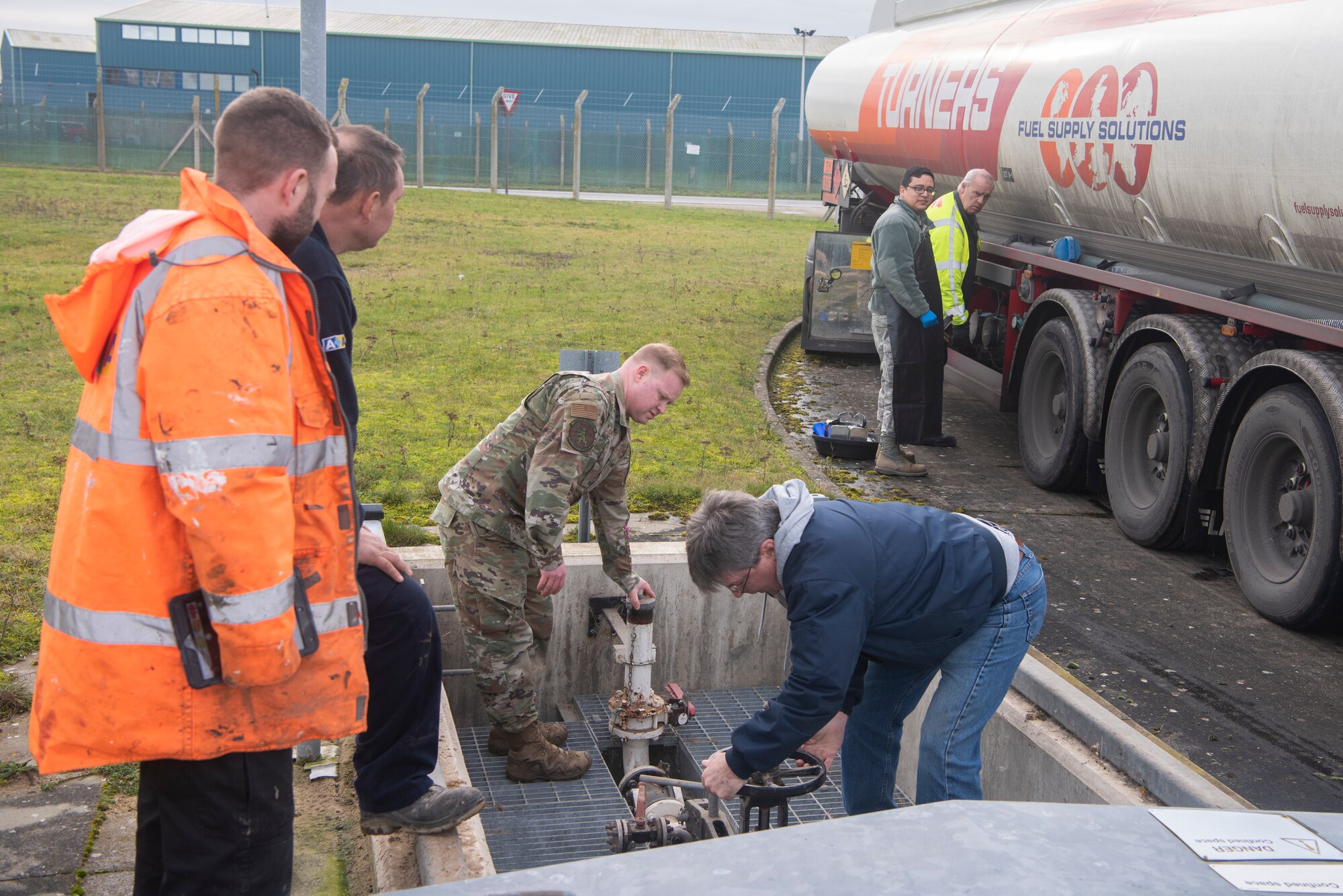 Master Sgt. Joseph Feiss, 100th Logistics Readiness Squadron noncommissioned officer in charge of fuels environmental safety office, and Alan VanDriesen, Maytag Aircraft Corporation terminal superintendent, open the valve to storage facilities Jan. 27, 2020, at RAF Mildenhall, England. The pipes must be opened to allow fuel to flow from the tanker truck into the underground tanks. (U.S. Air Force photo by Airman 1st Class Joseph Barron)