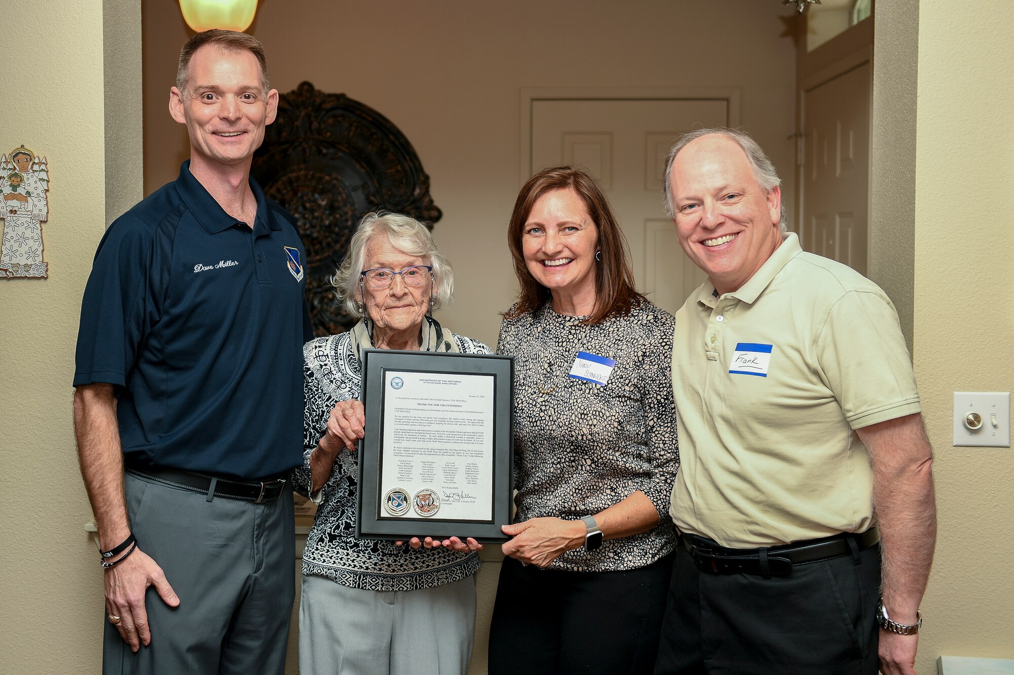 Four people pose for a photo with a certificate of thanks.