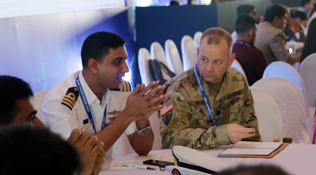 Sailor and soldier talk at table.