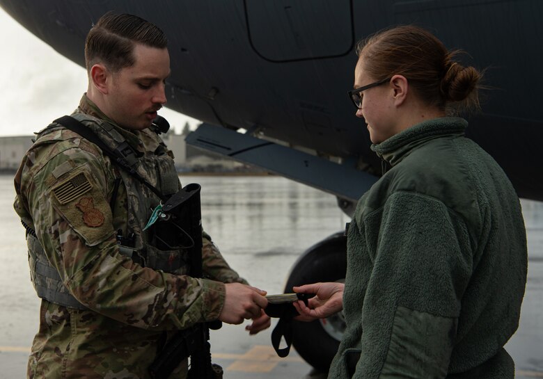Staff Sgt. Brandon Grimes, 627th Security Forces Squadron response team leader, checks a maintenance Airman’s flight line badge to ensure she is authorized to be on the flight line at Joint Base Lewis-McChord, Wash., Dec. 12, 2019. Grimes and other flight line security Airmen patrol the flightline’s perimeter to ensure only authorized are personnel have access. (U.S. Air Force photo by Senior Airman Tryphena Mayhugh)