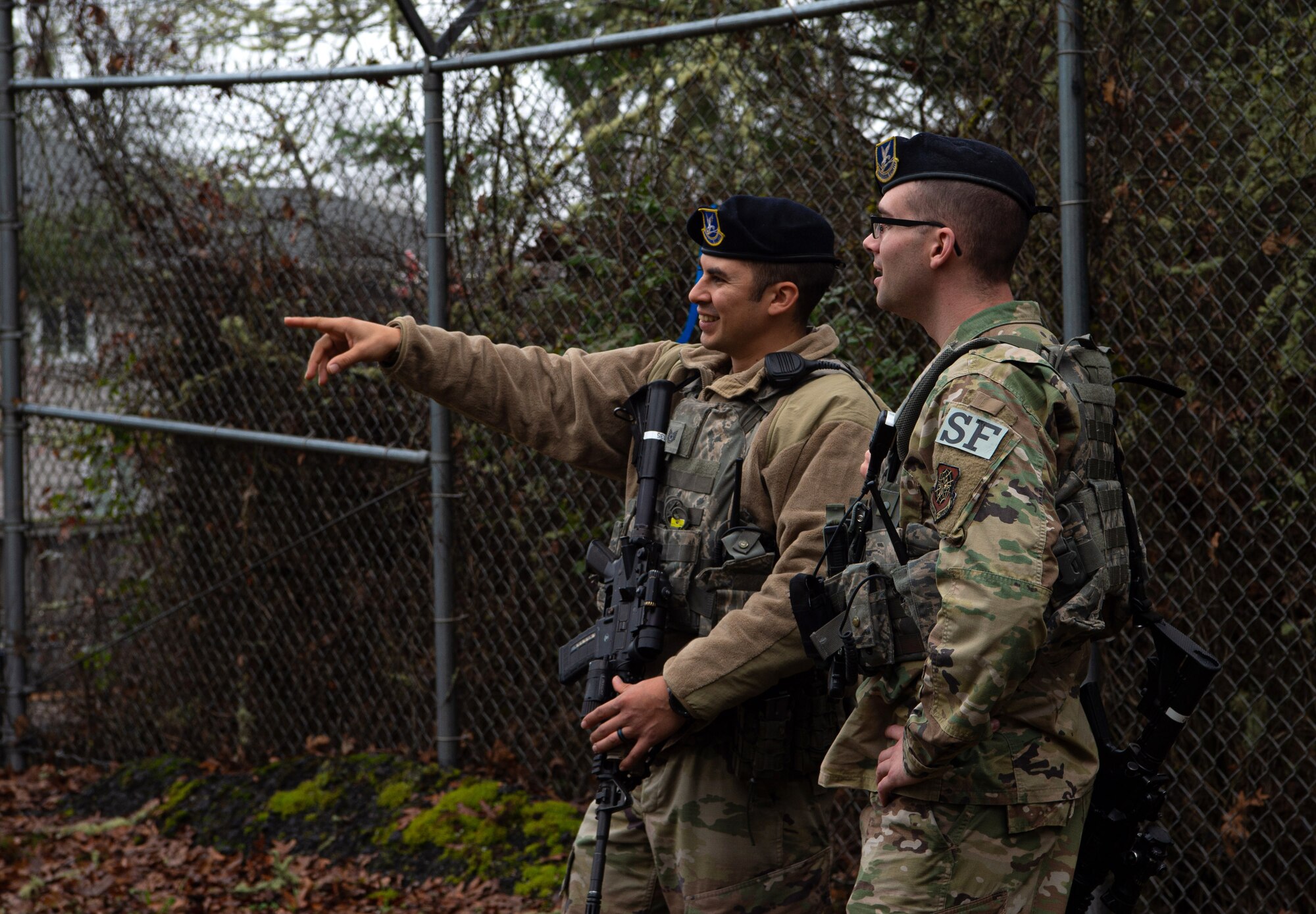 Tech. Sgt. Jesse Reyes, 627th Security Forces Squadron (SFS) combat arms instructor, points out a place in the flight line fence that needs repairs to a coworker at Joint Base Lewis-McChord, Wash., Dec. 4, 2019. 627th SFS flight line security Airmen patrol the fenceline looking for holes to be patched up by contractors. (U.S. Air Force photo by Senior Airman Tryphena Mayhugh)