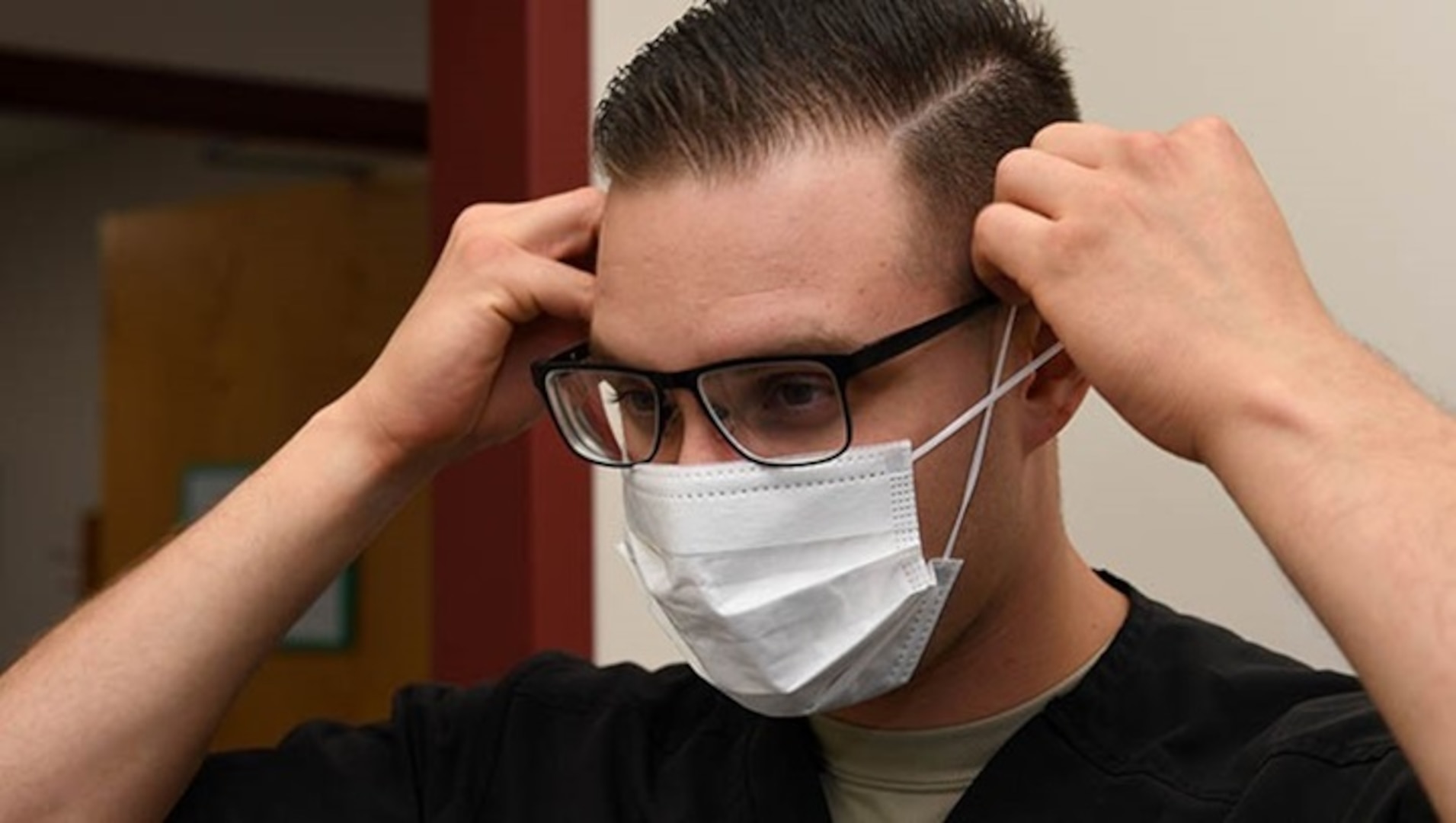 A dental assistant with the 319th Medical Group, demonstrates proper sanitary procedure by putting on a face mask at the medical treatment facility on Grand Forks Air Force Base, N.D. (U.S. Photo by Airman 1st Class Elora J. Martinez)