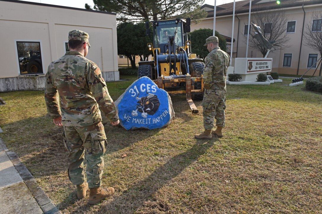 U.S. Airmen from the 31st Civil Engineer Squadron deliver a spirit rock to the front of the 31st Fighter Wing headquarters building at Aviano Air Base, Italy, Jan. 30, 2020. Capt. William Steers with the 31st CES painted the rock to represent their squadron.