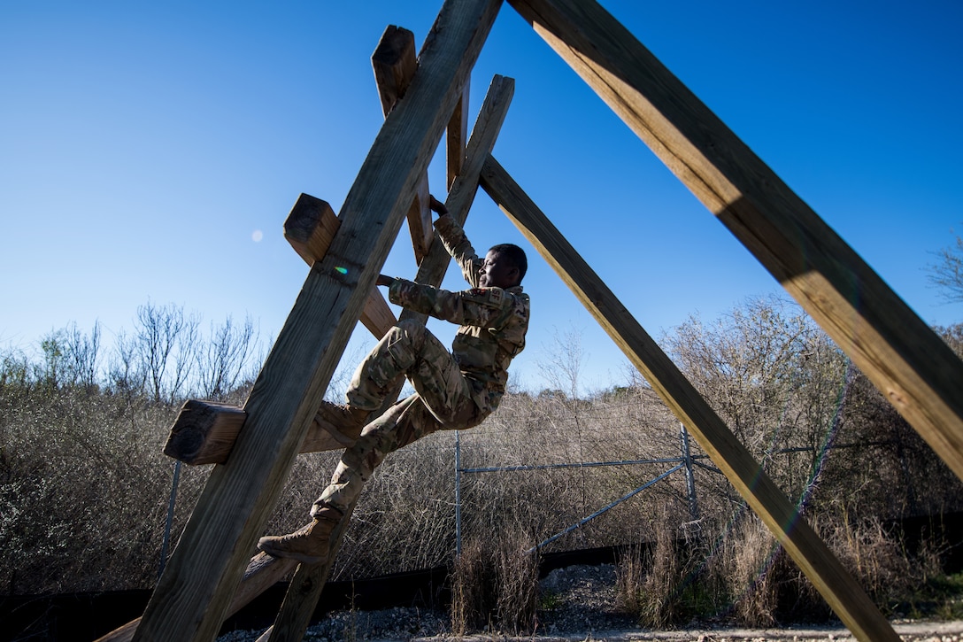 An airman climbs up a large ladder-like obstacle.