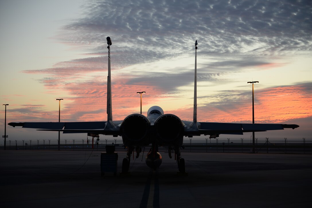 A fighter jet sits on tarmac at dusk.