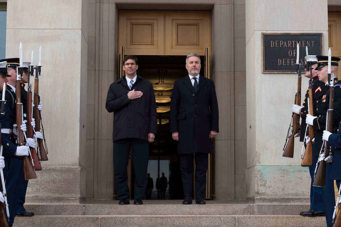 Two men stand at the top of some steps at the Pentagon.