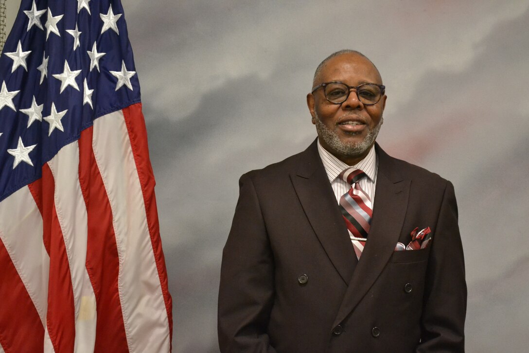 Man stands beside American flag.