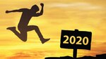 A silhouette of a person jumping toward a sign saying "2020" with a sunrise