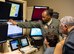 Lt. Col.  Michawn, 17th Attack Squadron director of operations, teaches Iron Sharpens Iron Mentoring youth how to fly the MQ-9 Reaper in a flight simulator at Creech Air Force Base