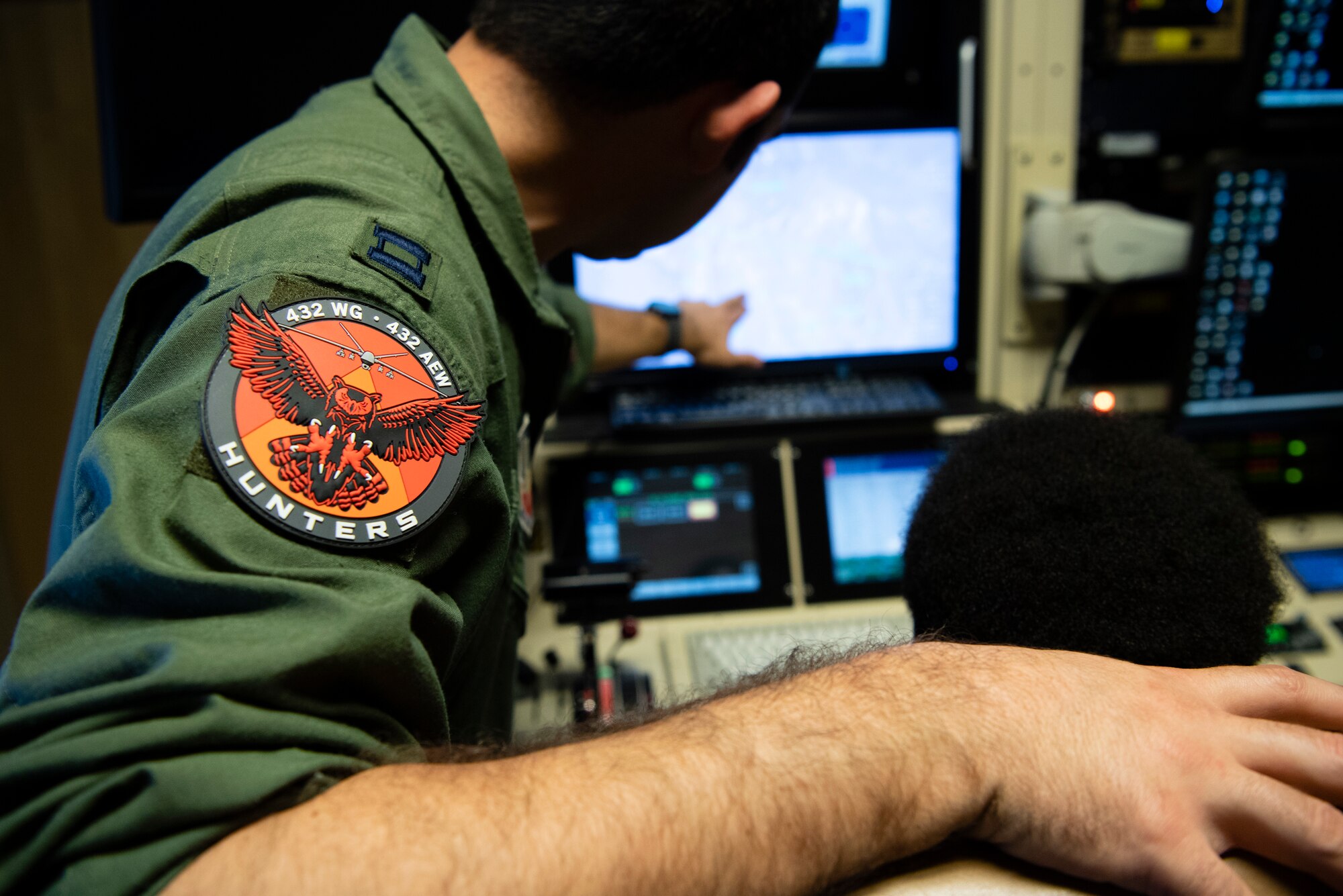 Capt. Marcus, 432nd Wing executive officer, teaches an Iron Sharpens Iron Mentoring youth how to fly the MQ-9 Reaper in a flight simulator at Creech Air Force Base, Nevada