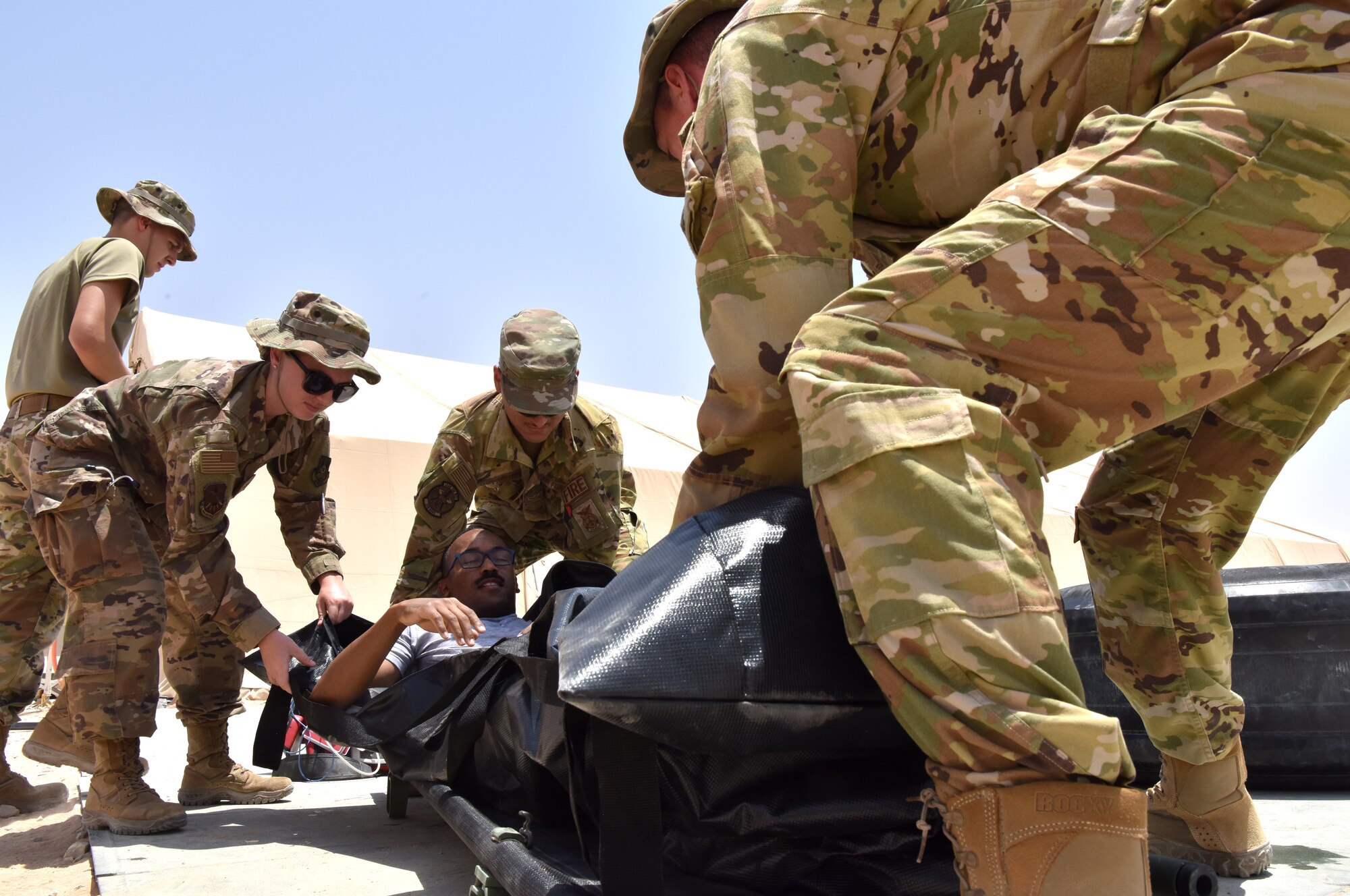 Medic Airmen from the 378th Expeditionary Medical Squadron train during a heat injury, rapid cool protocol exercise with firefighters from the 378th Expeditionary Civil Engineer Squadron at Prince Sultan Air Base, Kingdom of Saudi Arabia, July 1, 2020. Rapid response time to heat injuries is crucial for life-saving treatment for a patient. (U.S. Air Force photo by Master Sgt. Benjamin Wiseman)