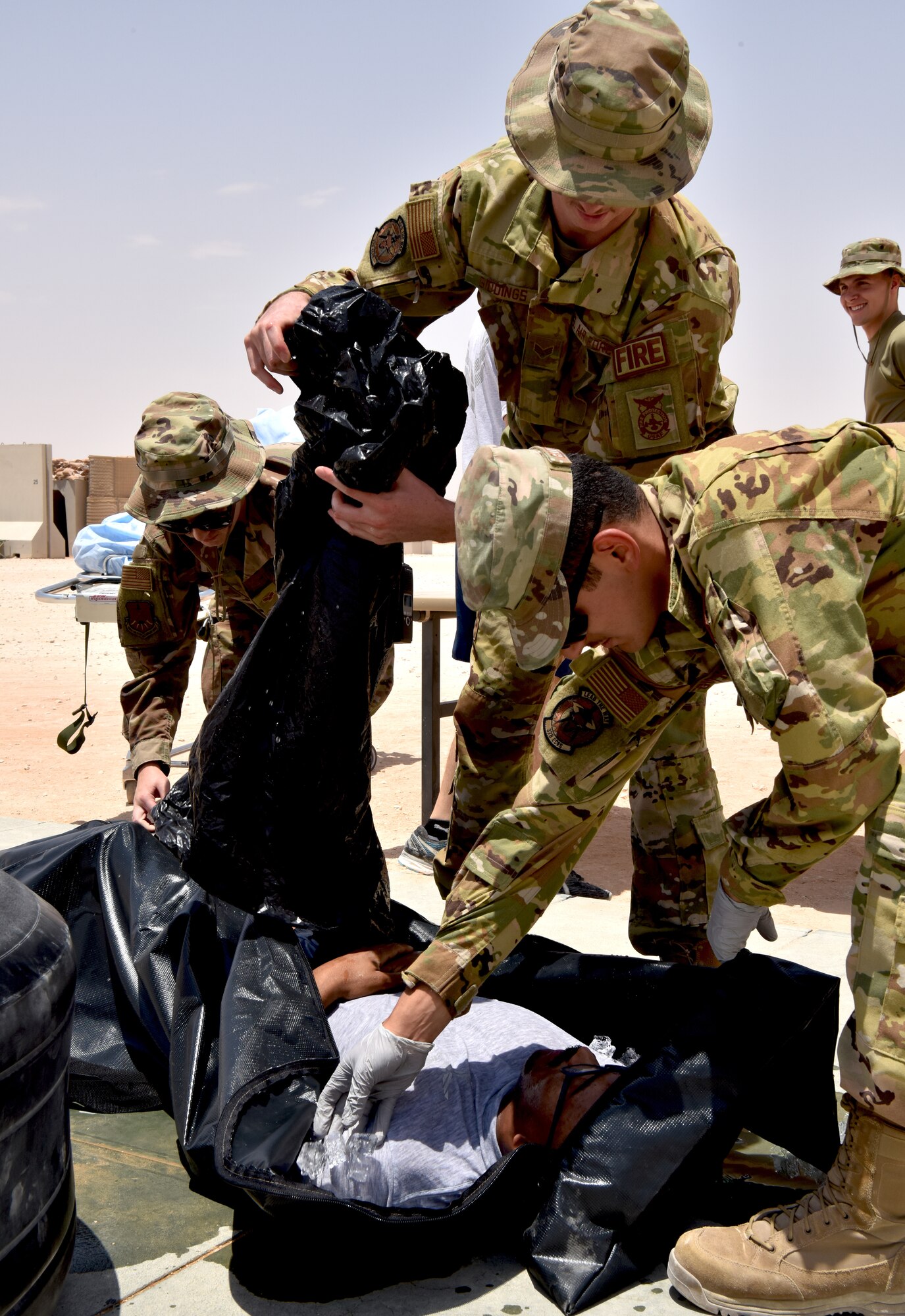 Medic Airmen from the 378th Expeditionary Medical Squadron train during a heat injury, rapid cool protocol exercise with firefighters from the 378th Expeditionary Civil Engineer Squadron at Prince Sultan Air Base, Kingdom of Saudi Arabia, July 1, 2020. Rapid response time to heat injuries is crucial for life-saving treatment for a patient. (U.S. Air Force photo by Master Sgt. Benjamin Wiseman)