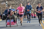 IMAGE: DAHLGREN, Va. - Naval Surface Warfare Center Dahlgren Division (NSWCDD) engineer Benjamin Tritt, cofounder of the Fredericksburg Ainsley's Angels Ambassadorship, nears the finish line of a 5K road race pushing a specially designed running 'chariot'. Tritt will be honored with the NSWCDD Distinguished Community Service Award at the upcoming virtual honorary awards ceremony scheduled to be broadcast in July.