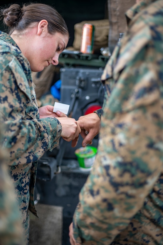Navy Petty Officer 2nd Class Jenna Bentle, a hospital corpsman with Special Purpose Marine Air-Ground Task Force - Southern Command, treats a minor abrasion during a field exercise at Camp Lejeune, North Carolina, June 9, 2020. The FEX provides the Marines and Sailors the opportunity to stay proficient with their equipment and refine their tactical skill sets. SPMAGTF-SC is poised to conduct crisis response, general engineering training, and theater security operations alongside partner nation militaries in Latin American and the Caribbean. Bentle is a native of Green Bay, Wisconsin. (U.S. Marine Corps photo by Sgt. Andy O. Martinez)