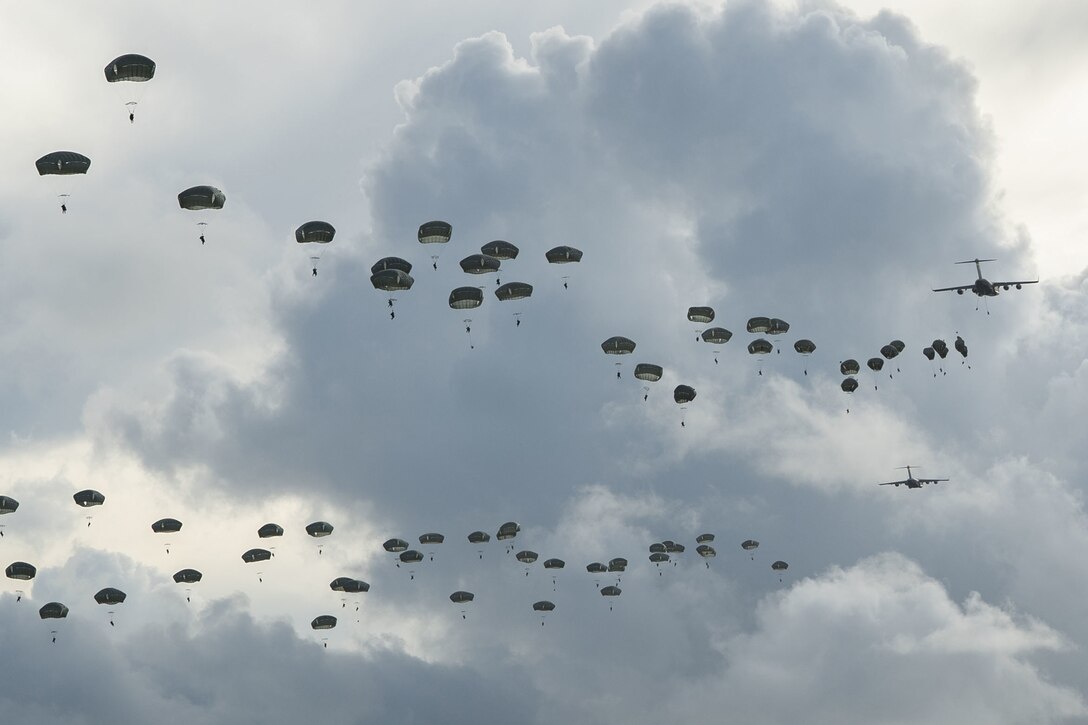 A large group of paratroopers float down to the ground.