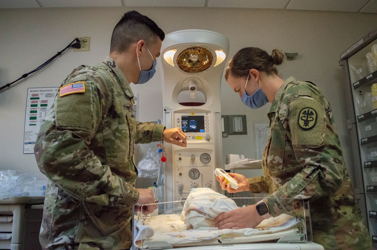 Two Army doctors work in a pediatrics ward.