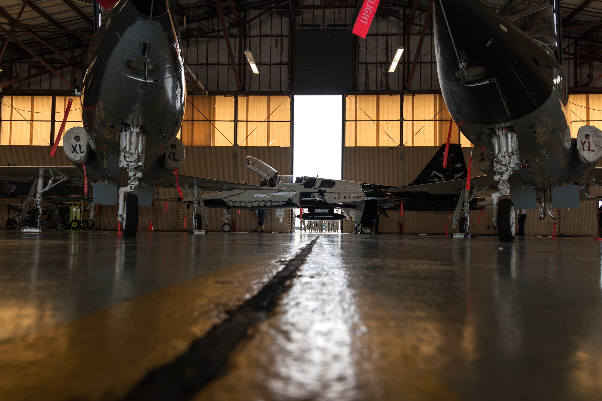 The hangar doors open to reveal the T-38C Talon aircraft, painted with a first assignment instructor pilot theme, as pilots and maintainers alike watch eagerly from outside, June 26, 2020 at Laughlin Air Force Base, Texas. “The best part was seeing Valentin’s face and how excited all the pilots were,” Juan Gonzalez, 47 MXD corrosion control work lead, said. “Col. Jones complimented our work and that meant a great deal to us. We feel proud of the work we did.” (U.S. Air Force Photo by Senior Airman Anne McCready)