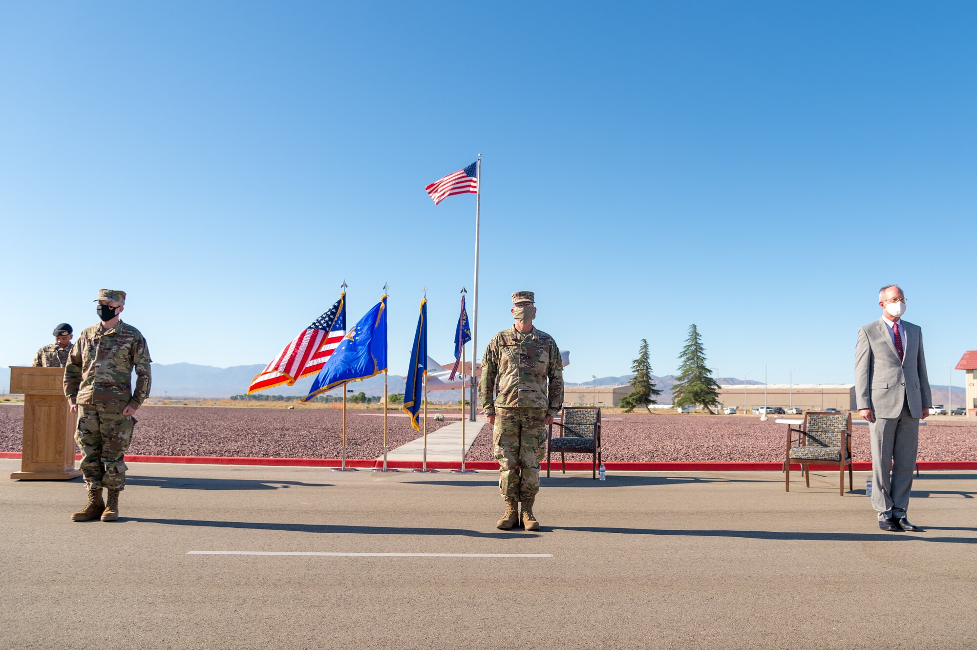 Brig. Gen. Matthew Higer, the 412th Test Wing Commander, Col. Dwayne Robison, the outgoing Operating Location Air Force Plant 42 Director, and incoming Director Dr. David Smith stand at attention during a Change of Leadership Ceremony at Plant 42 in Palmdale, California. (Air Force photo by Ethan Wagner)