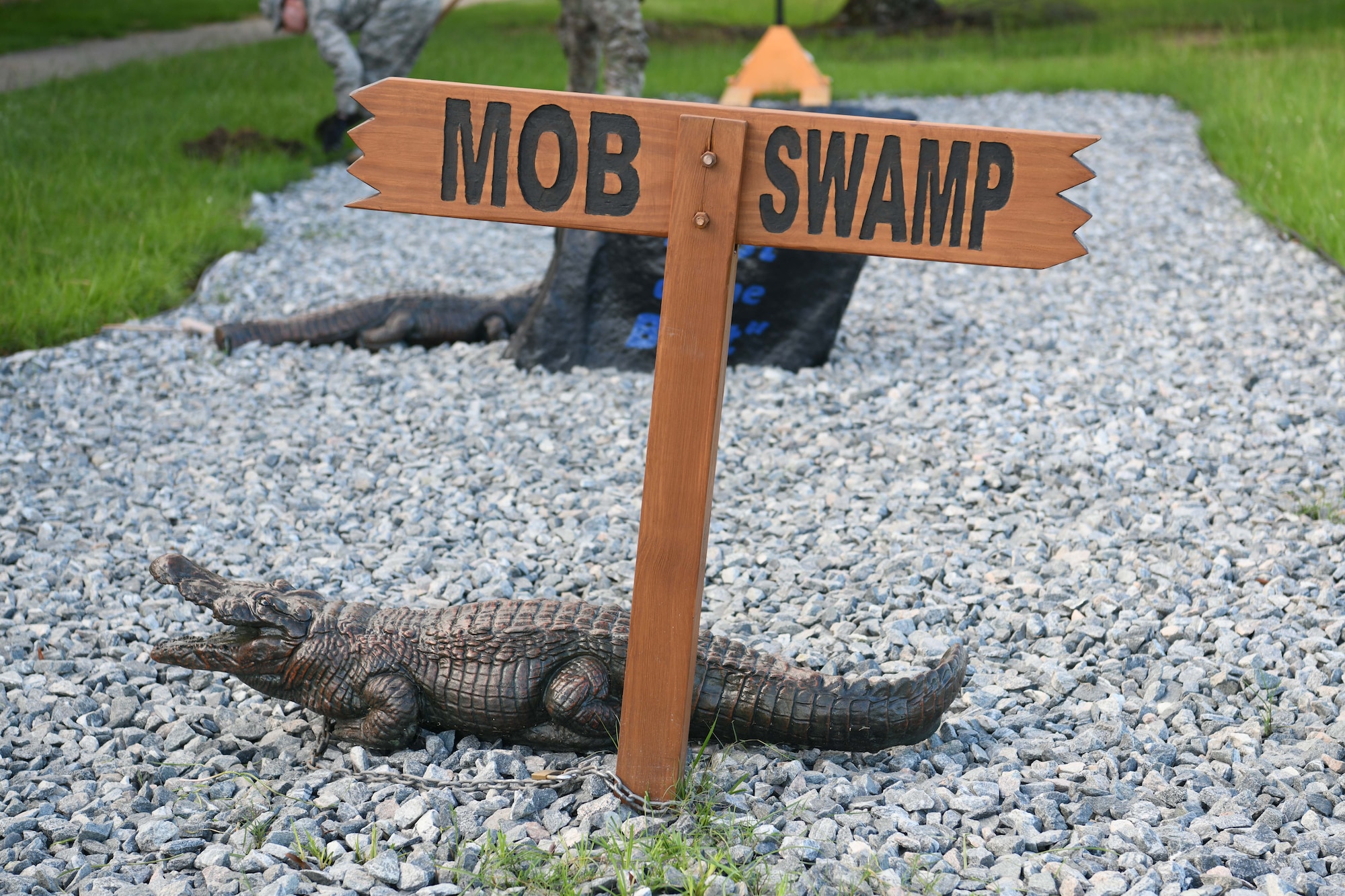 Photo shows a concrete alligator sitting by a sign that says "MOB SWAMP."