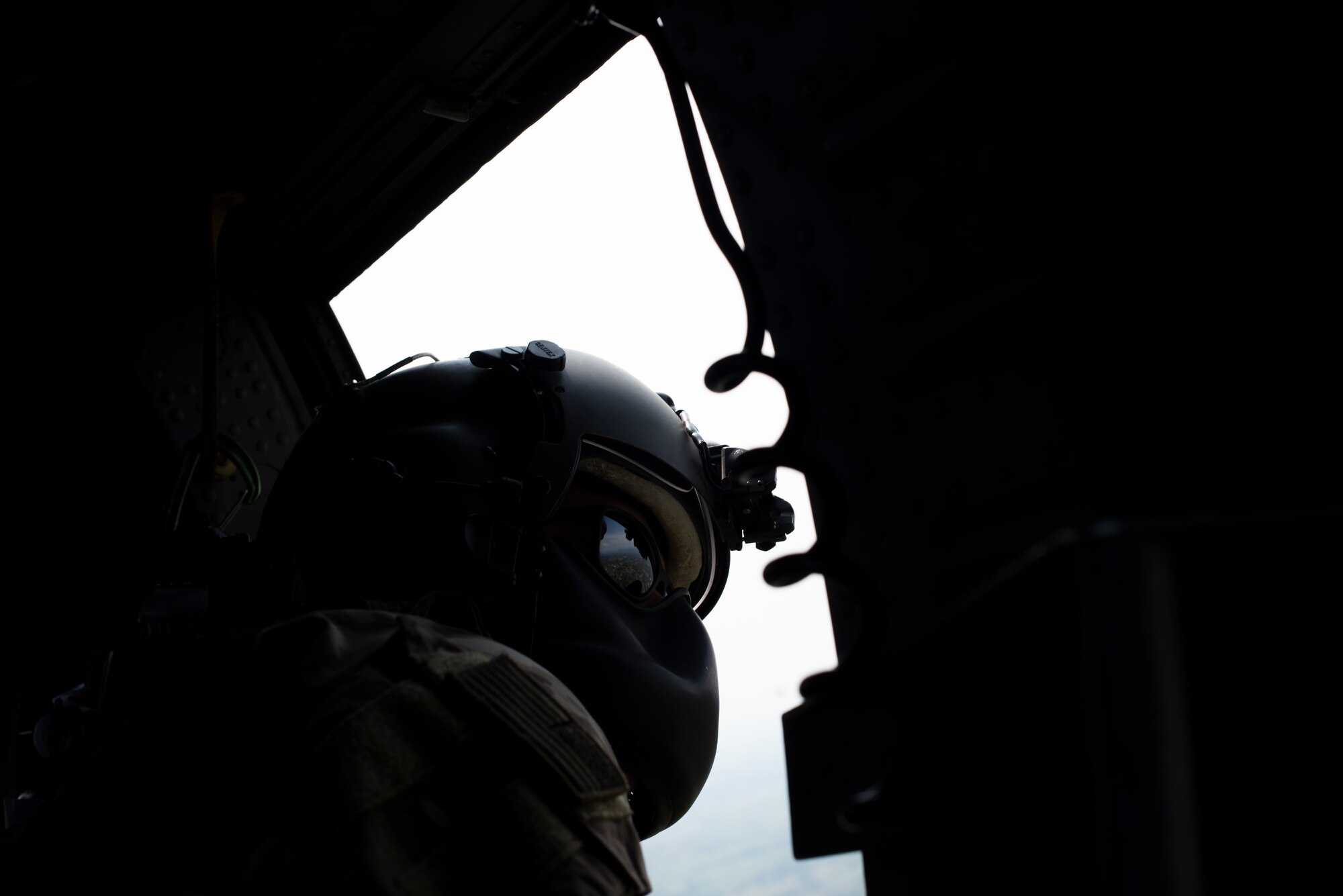 An Airman from the 56th Rescue Squadron looks out of an HH-60G Pave Hawk during Operation Porcupine over a military training area in Osoppo, Italy, June 30, 2020. Operation Porcupine is a combat search and rescue exercise requiring Aviano’s 510th Fighter Squadron, 56th and 57th Rescue Squadron, and 606th Air Control Squadron to work together to accomplish the mission.  (U.S. Air Force photo by Senior Airman Caleb House)