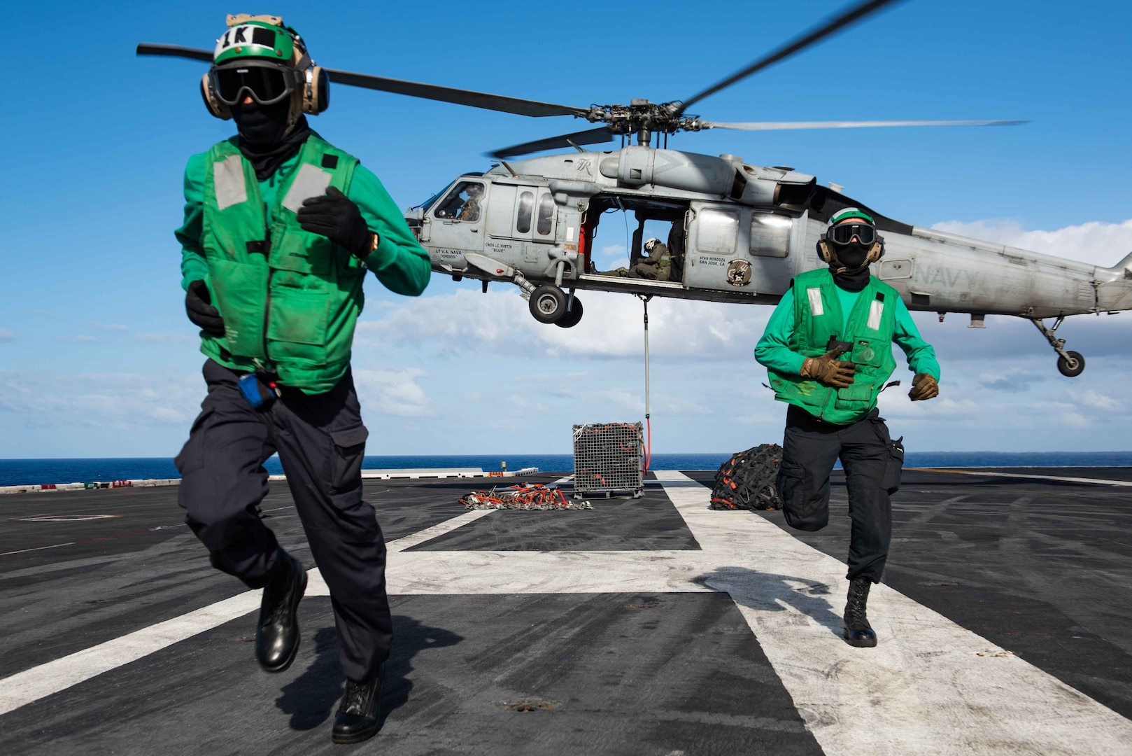 Sailors move away from MH-60S Sea Hawk helicopter assigned to “Eightballers” of Helicopter Sea Combat Squadron 8 as it lifts cargo from flight deck of USS Theodore Roosevelt during replenishment-at-sea with USNS Henry J. Kaiser, Pacific Ocean, July 1, 2020 (U.S. Navy/Erik Melgar)