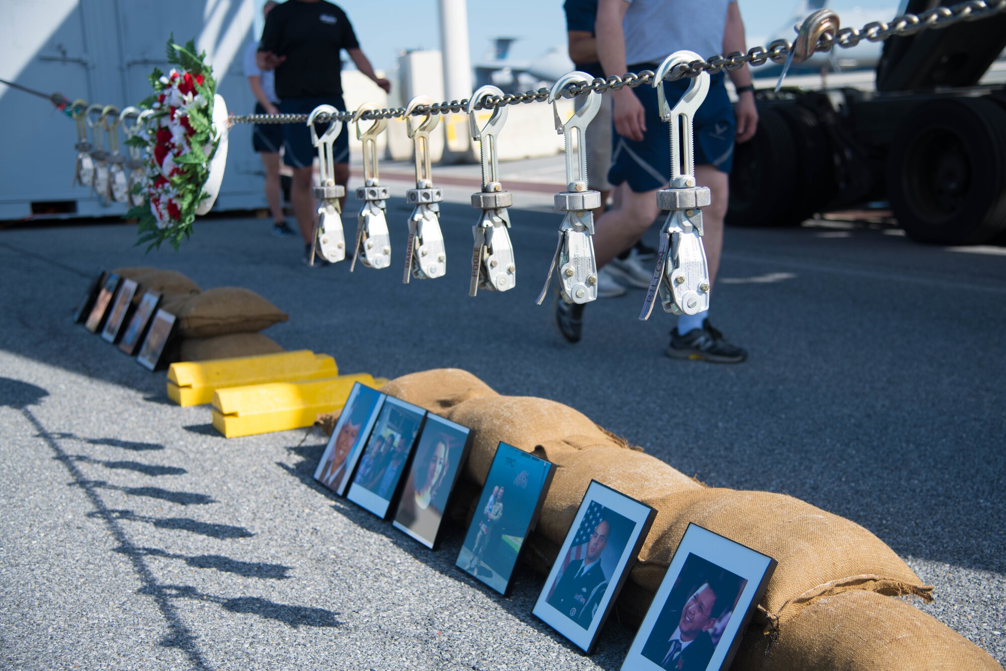 Tie-downs are hung in memory of fallen Port Dawgs during a ceremony prior to the annual Port Dawg Memorial 5K June 29, 2020, at Dover Air Force Base, Delaware. Tie-downs, an essential tool for the air transportation career, are locked to a chain with the name tapes of fallen members and hung above their portraits. (U.S. Air Force photo by Airman 1st Class Faith Schaefer)