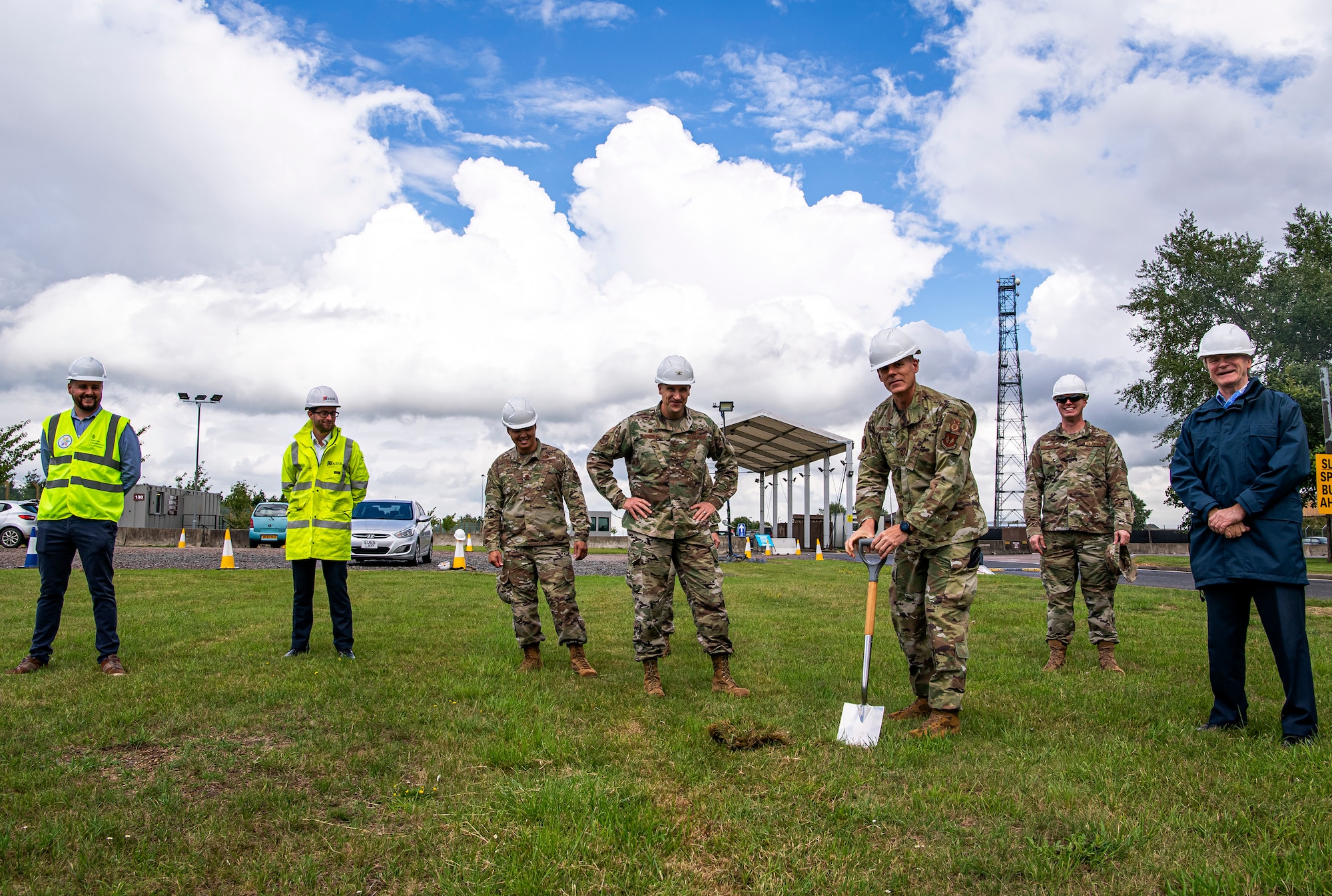 U.S. Air Force Chief Master Sgt. Michael Groder (center right), 423d Security Forces Squadron manager, breaks ground on a construction project for the main gate at RAF Alconbury, England, July 2020. This project will provide a large vehicle inspection station, channelized traffic flow for better security and improved safety for personnel. Construction will commence on July 6, 2020 and effective from that date, installation entry and exit procedures will be modified to support the construction project. (U.S. Air Force by Senior Airman Eugene Oliver)