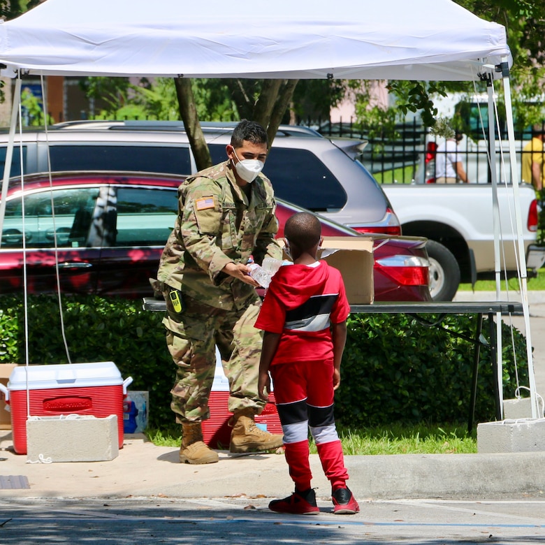 A soldier gives a bottle of water to a boy.