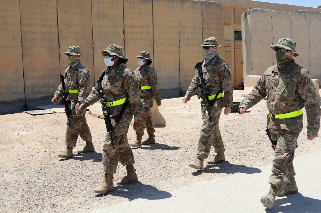Socially distanced soldiers wearing face masks practice drill and ceremonies.
