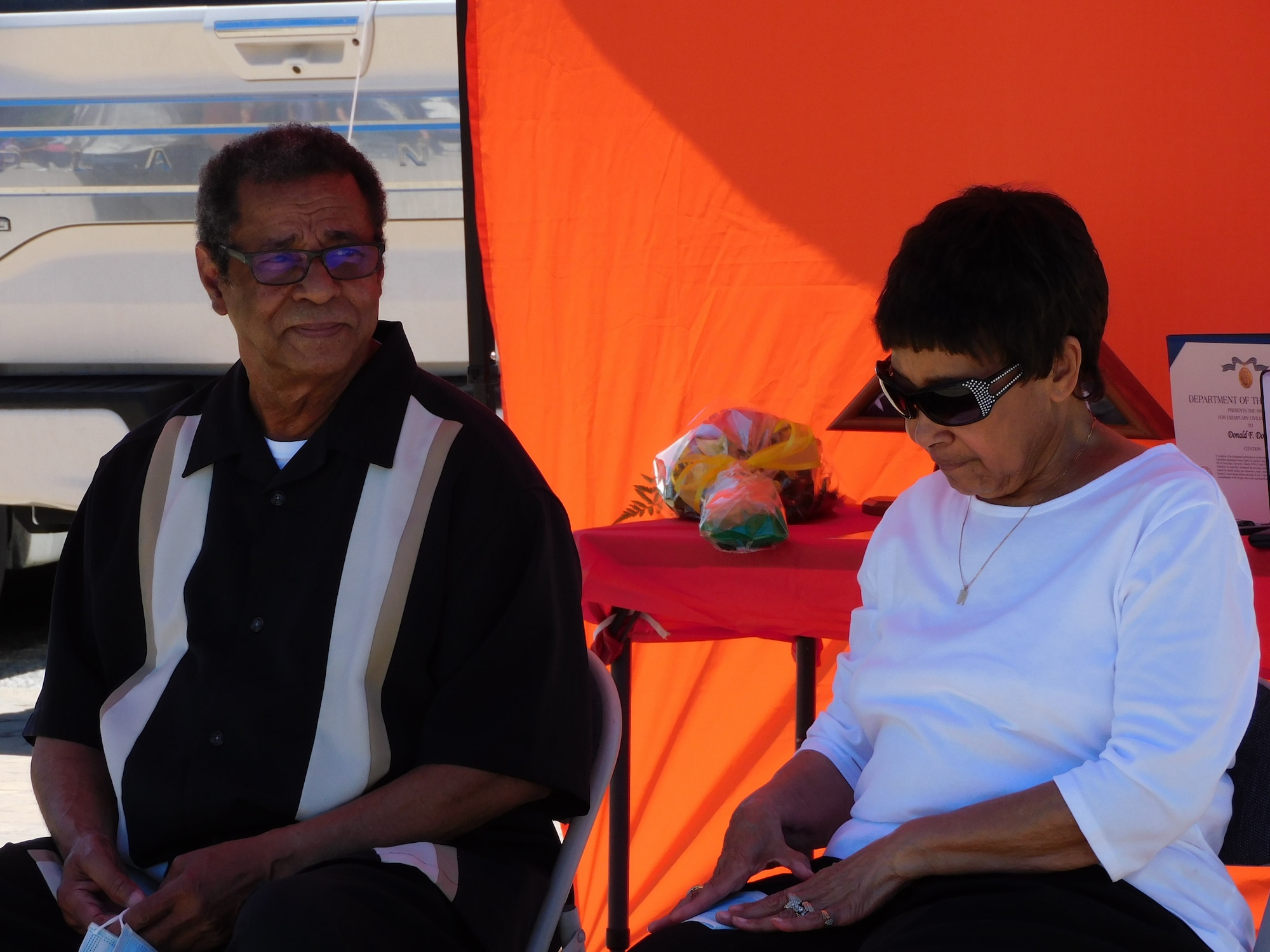 Donald F. Douglas and his wife Mary sit under a tent during the retirement ceremony.