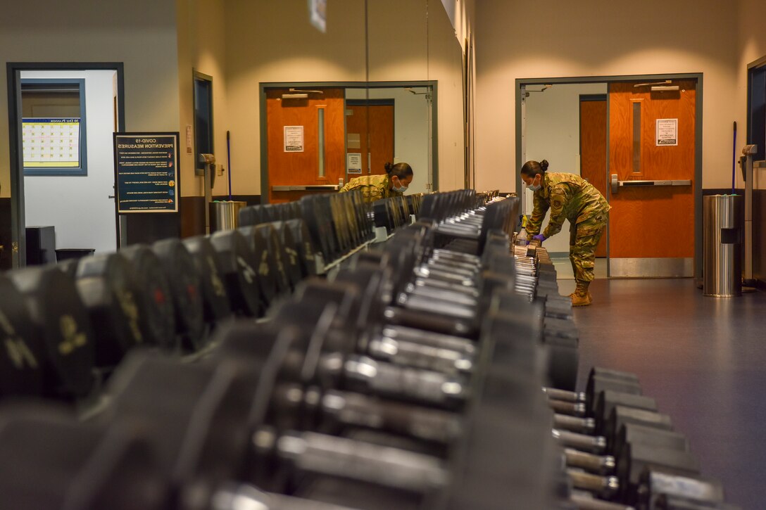 An airman sanitizing fitness equipment.