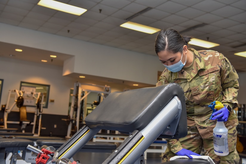 An airman sanitizes fitness equipment.